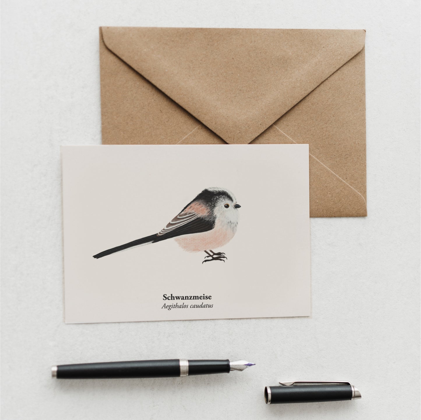 Naturpostkarte mit Schwanzmeise Illustration und braunem Umschlag auf weißem Hintergrund.