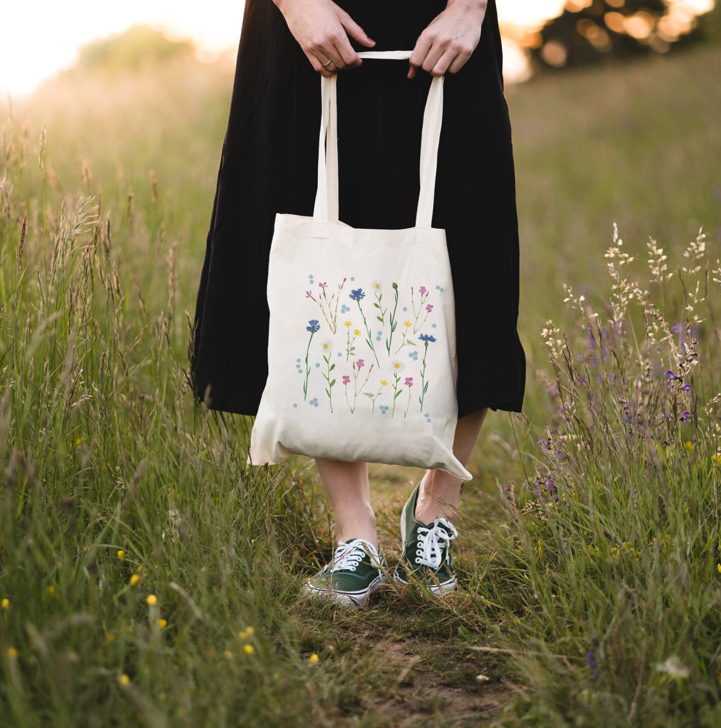 Wildblumen-Tasche in der Hand gehalten, stehend im hohen Gras
