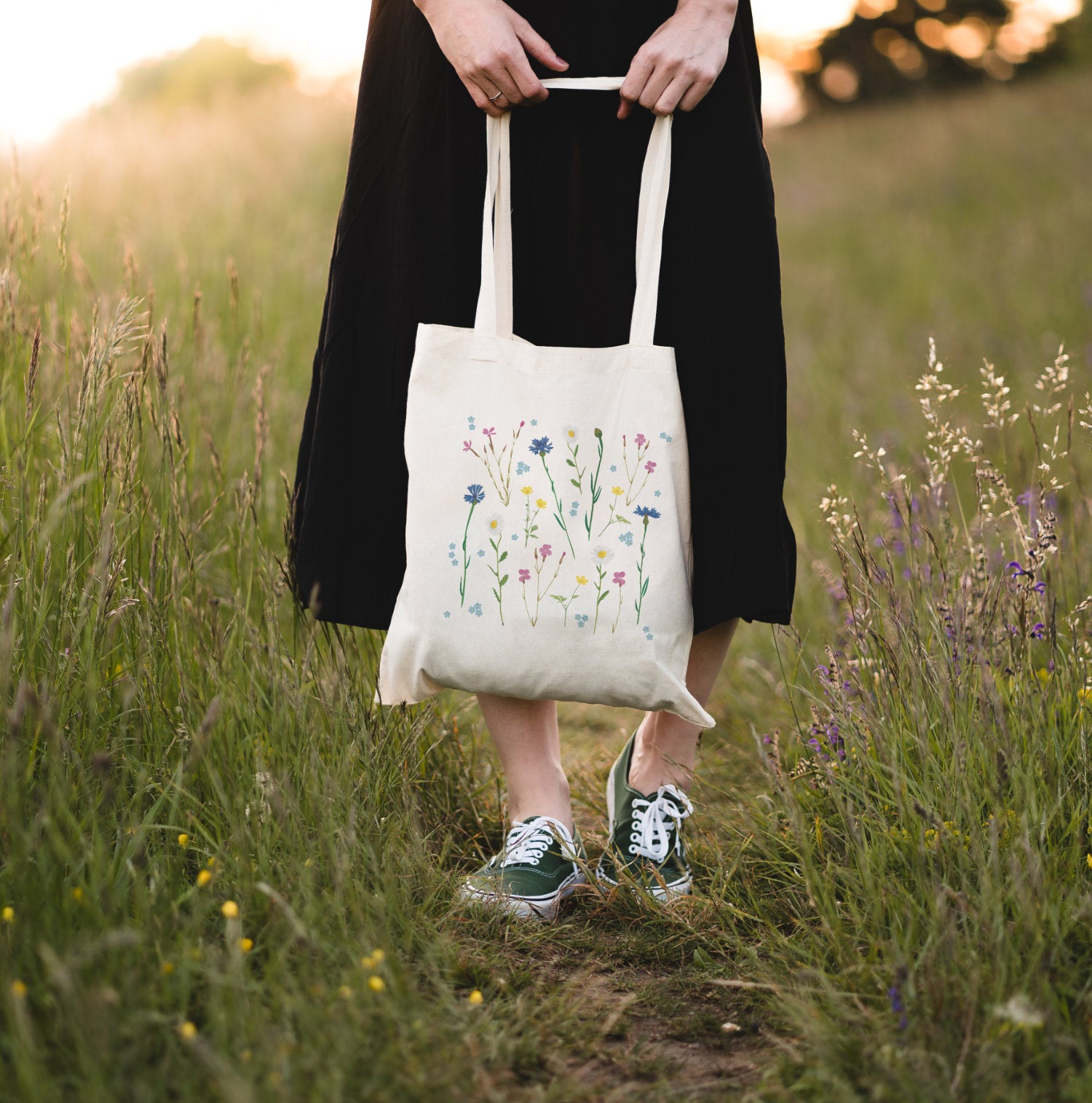 Wildblumen-Tasche in der Hand gehalten, stehend im hohen Gras